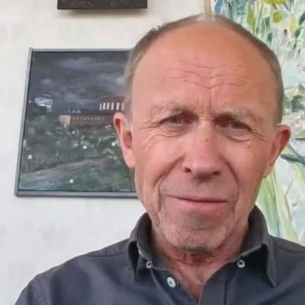 Forskaren Max Strandberg sitter framför en vägg med tavlor.