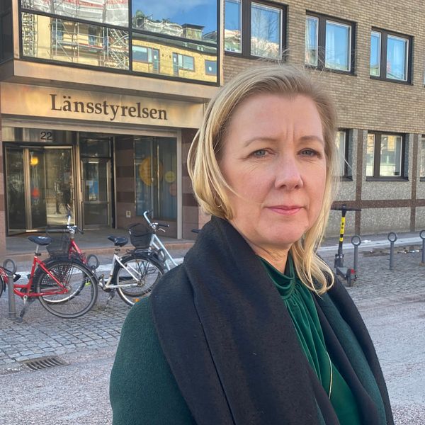 Länsrådet Anna Olofsson i grön outfit står framför Länsstyrelsens port i Örebro.
