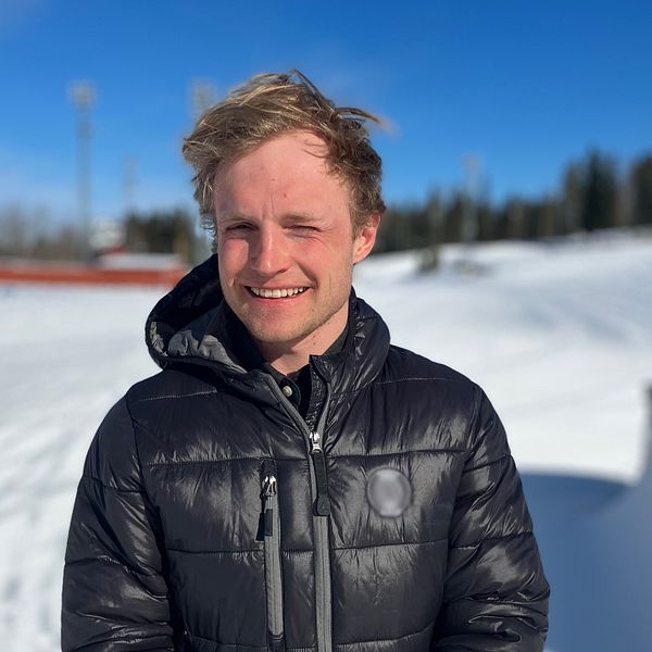 Björn Sandström, längdskidåkare står på Östersunds skidstadion och kisar i solen.