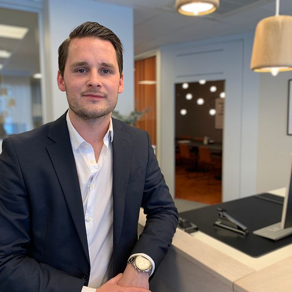 Fastighetsmäklaren Alexander Parmhed sitter på sitt kontor vid ett arbetsbord.