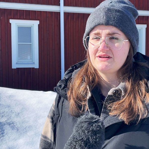 Jessicas Holmström i Idre intervjuas. Hon har långt mörkt hår, grå mössa och glasögon. Bakom henne syns snö och ett rött hus med vita knutar.