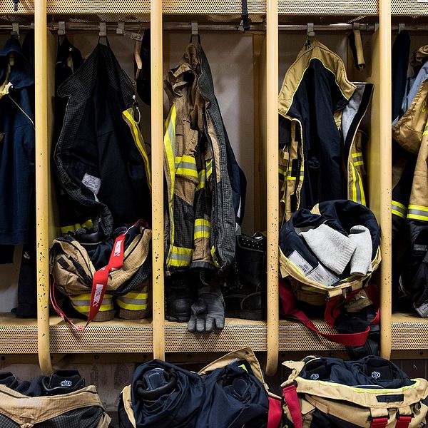 Bild från ett omklädningsrum med brandmännens arbetskläder upphängda.