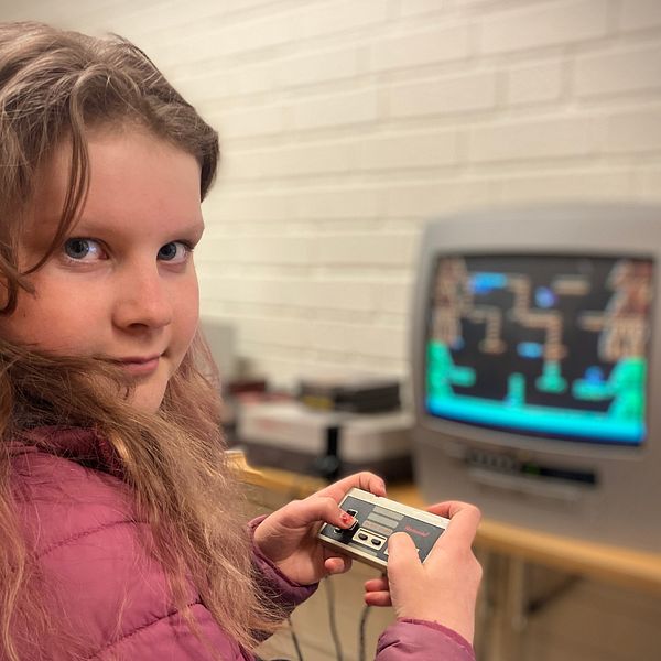 Noomi Jonsson, 11 år, håller upp en gammal tv-spelkontroll och tittar in i kameran.