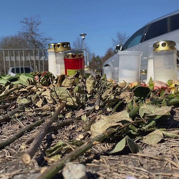 Ljuslyktor och torkade blommor. I bakgrunden syns en bil.