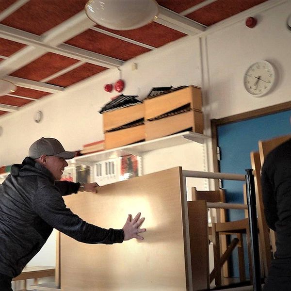 lärare hjälps åt att blockera en dörr på insidan av ett klassrum på Vallaskolan i Östersund. Bord och stolar placeras i en stor hög.