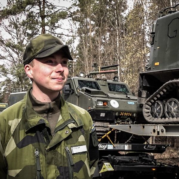 Värnpliktige Gustavsson som är en de vid Dalregementet som nu ansluter till övningen Aurora-23. Han står vid en lastbil som lastad med en bandvagn och är på väg söderut där de ska agera en fiendebataljon tillsammans med delar från Livgardet och I21.