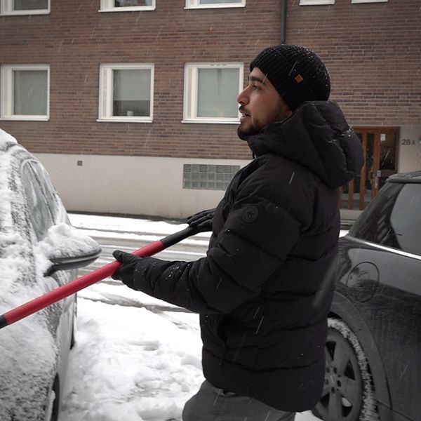Mawlod Hajo står i ett snöigt Östersund och skottar av sin bil från snö.
