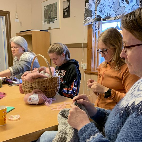 Fem kvinnor runt ett bord som handarbetar på en syjunta i Orsa