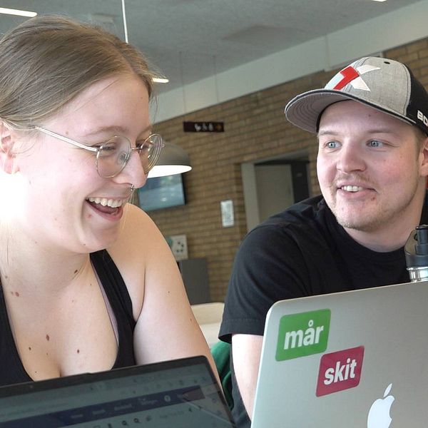 Dorothea Clason har uppsatt hår och glasögon. Hon skrattar och tittar mot en datorskärm framför sig. Olle Forss sitter bredvid och tittar på henne. I bakgrunden syns det att de sitter på Umeå universitet.