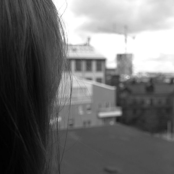 En kvinna tittar ut över takåsar i en stad
