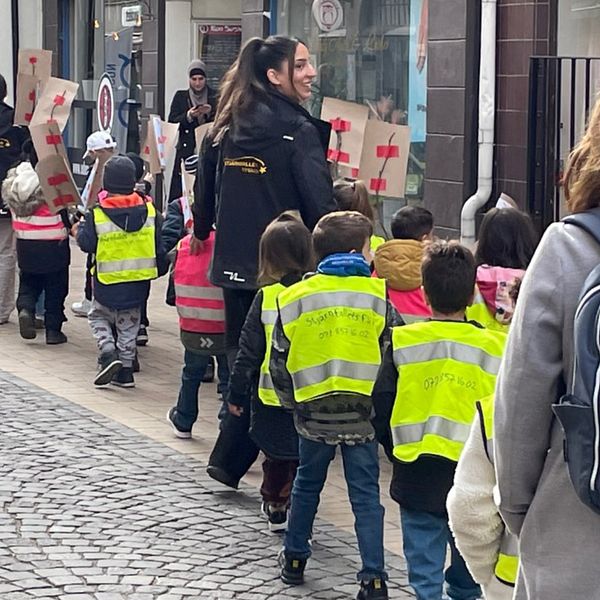 Barn och vuxna från förskola som går i ett demonstrationståg.