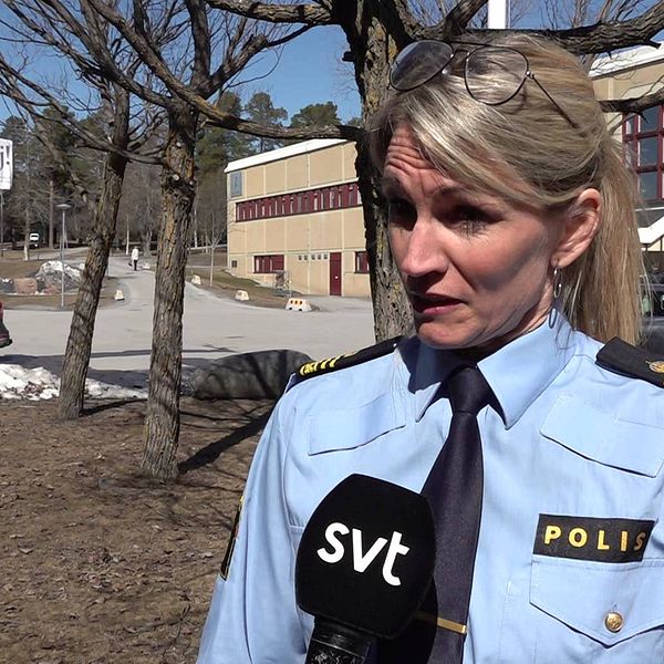Blond kvinna i poliskläder står utomhus och blir intervjuad.