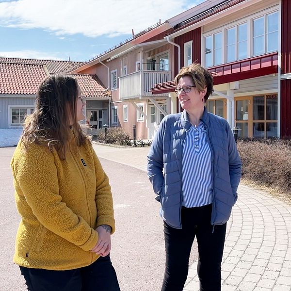 Två kvinnor på bild framför ett trähus i olika färger. Kvinnan till vänster har en gul fleecetröja, Jessica Holmström, och den andra kvinnan har en blå dunjacka, Monica Salmonsson.