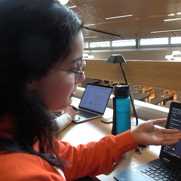 Utbytesstudenten Tomke D'Souza vid Luleå tekniska universitet sitter i biblioteket och visar ett program på sin bärbara dator.