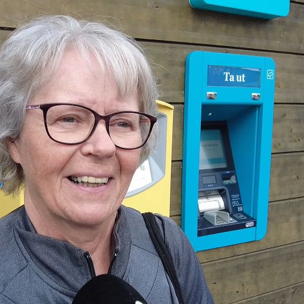en kvinna som står framför en uttagsautomat för kontanter