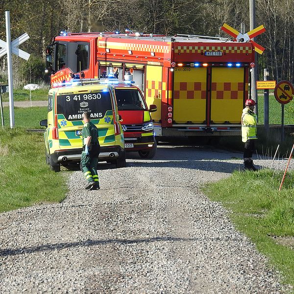 Ambulasn, brandbil och polisman syns i bild vid en järnvägskorsning.