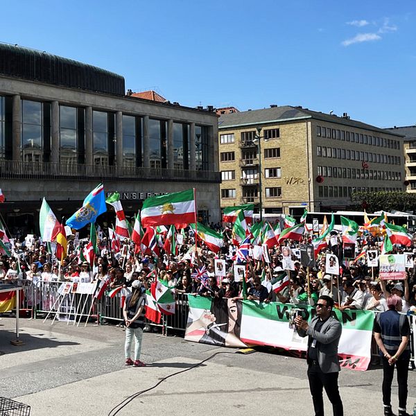 Götaplatsen i Göteborg en solig majdag. På bilden syns flera männsikor som demonstrerar mot den iranska regimen.