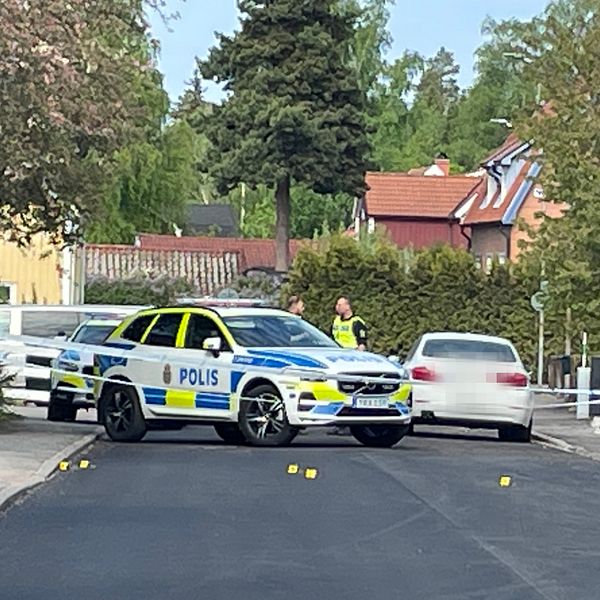 Polisbilar på bostadsgata med flera utmarkerade nummer för teknisk undersökning.
