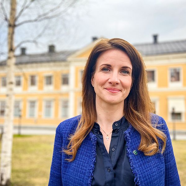 Effie Kourlos centerpartiet står framför gul träbyggnad i Östersund