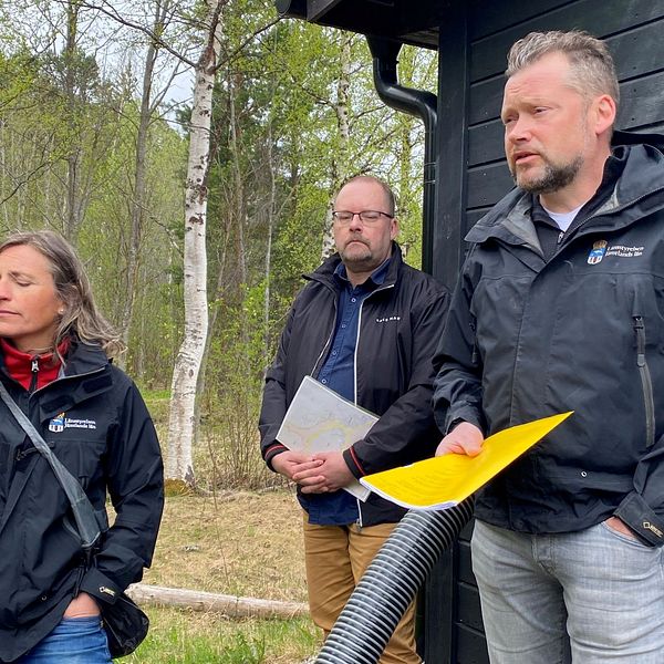 Anna Löfholm vattenhandläggare länsstyrelsen, Joakim Svensson, länsfiskekonsulent och Jens Fuchs, chef på Vattenenheten länsstyrelsen står utomhus med papper och kartor i händerna.