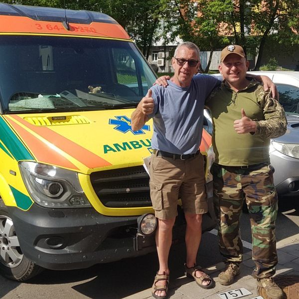 Hasse Hansson och en ukrainsk soldat framför ambulansen från Region Skåne.