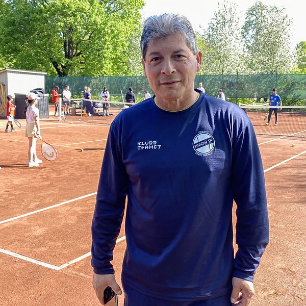 En man, Martin Mestanza projektledare för Tennis på gatan, står på en tennisbana och tittar in i kameran.