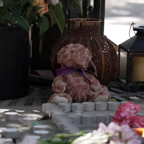 Blommor, ljus och en nalle vid minnesplatsen i Farsta där en 15-åring sköts ihjäl och tre personer skadades.