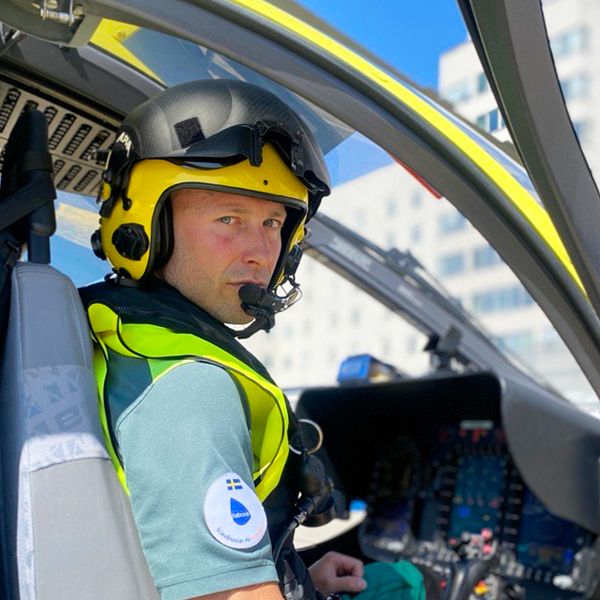 Tore Schultzberg, helikopterpilot, sitter i en helikopter. I bakgrunden Södersjukhuset.