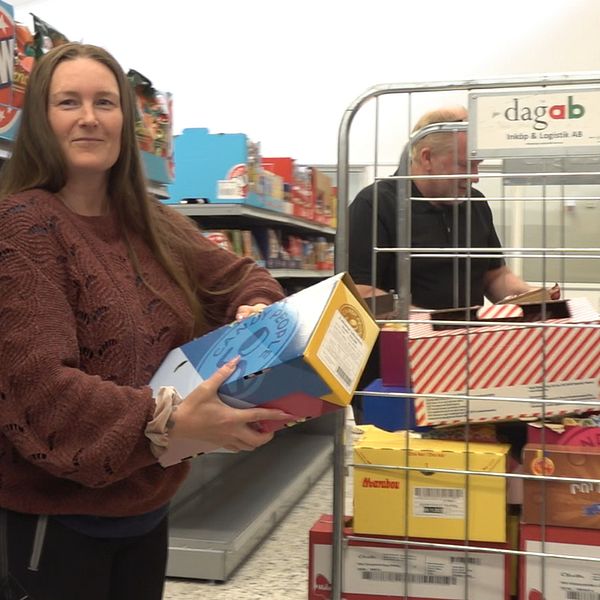 Pauline och Jörgen drar en vagn med varor förbi en hylla med chipspåsar i den obemannade butiken i Lögdeå.