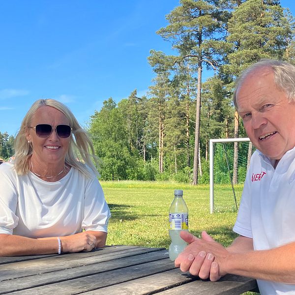 En man och en kvinna sitter på varsin sida av en parkbänk och tittar in mot kameran med ett leende. Båda har ett vitt plagg på överkroppen.