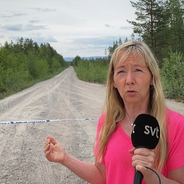 SVT:s reporter Marie Selander framför en polisavspärrning på en skogsbilväg i närheten av Vemhån.