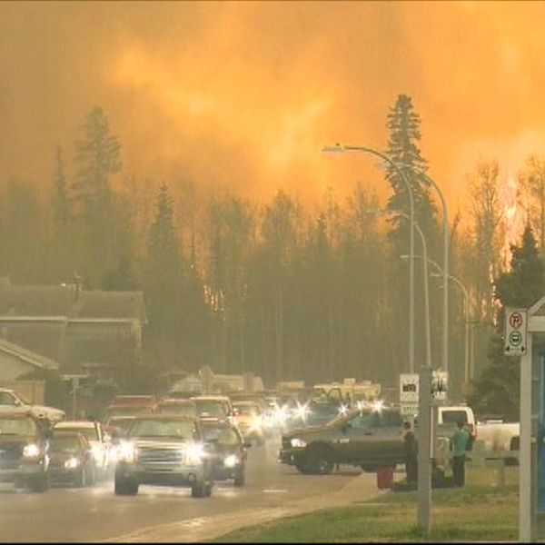 Fort McMurray 2016, himlen är färgad röd av en stor skogsbrand. Vägen är full av bilar då staden evakuerades.