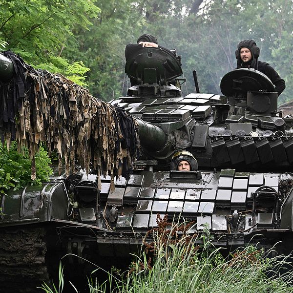 Ukrainsk T-72 stridsvagn kör genom lövskog.