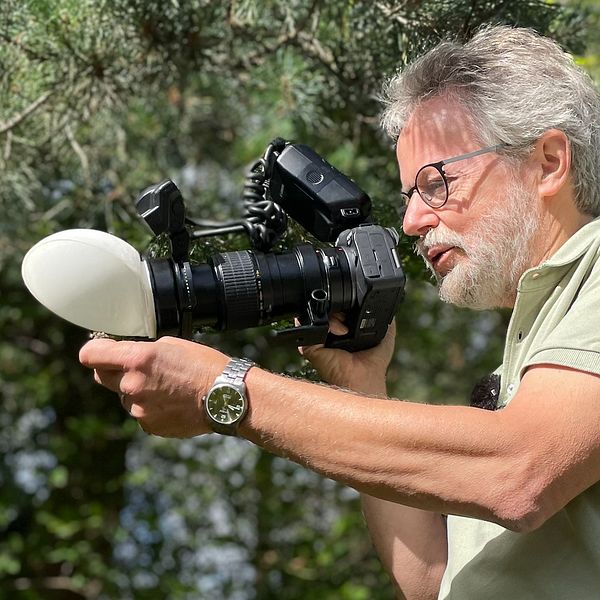 En man fotograferar en insekt med sin kamera.