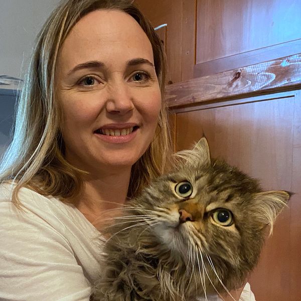 Bild på en medelålderskvinna som håller en katt i famnen.