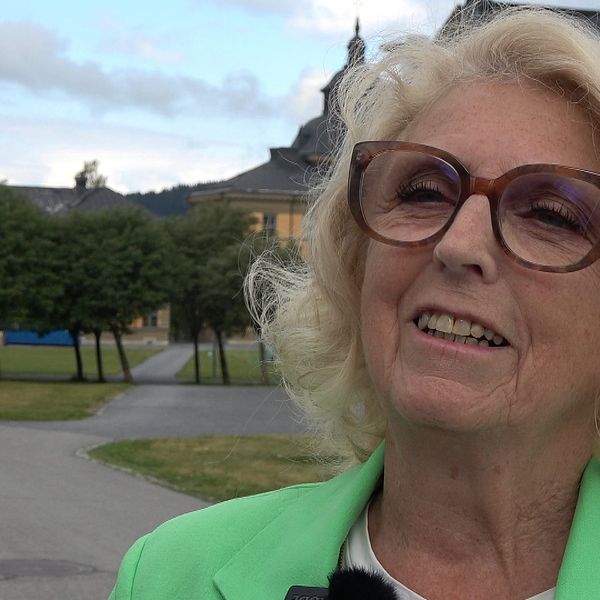 Gertrud Nygren en pensionär med blont axellångt hår och stora glasögon. Sommardag i bakgrunden och tre boxar med siffror 3,2,1 från övre vänstra hörn.