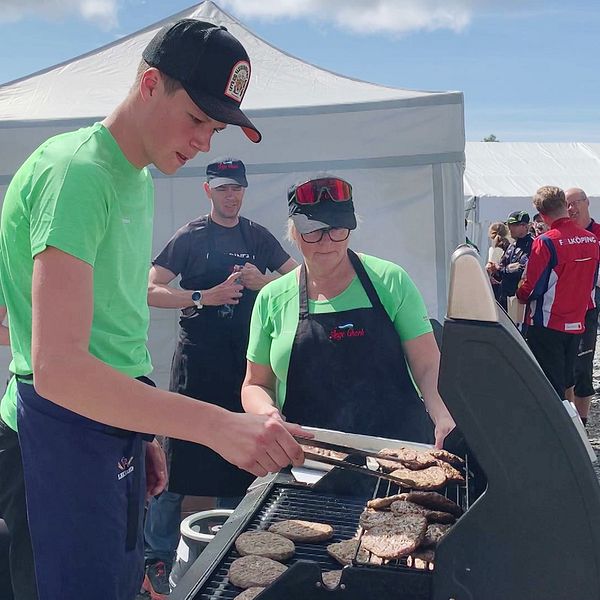 Hugo, en pojke i tonåren iklädd grön t-shirt och svart keps, och grillar hamburgare under O-ringen i Åre.