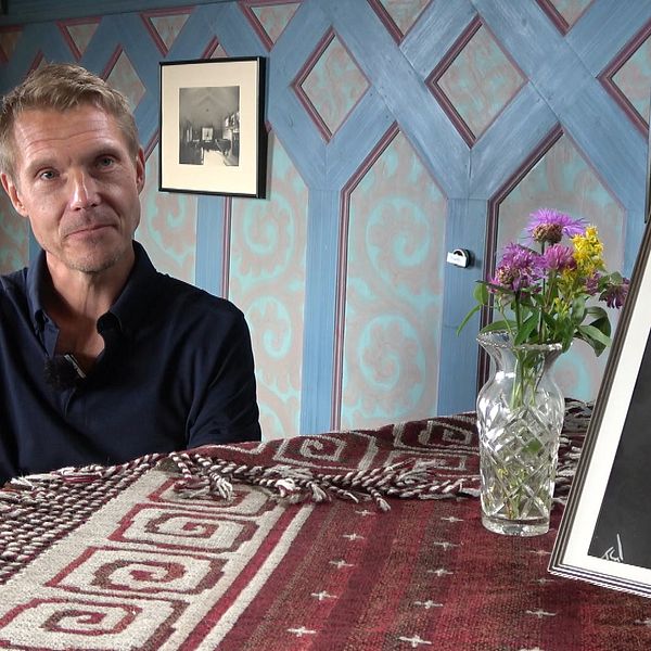 I stora salen i villa Sommarhagen, vid pianot sitter kompositören Mika Pelo. I förgrunden en bild på Peterson-Berger. Mika Pelo har en pikétröja och på pianot finns även en kristallvas med sommarblomster.