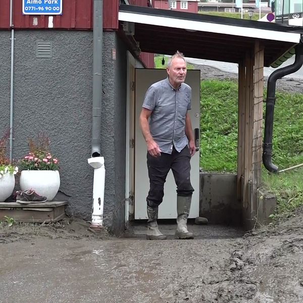 En företagare utanför sin lokal i centrala Åre där marken är lerig av översvämningen i Susabäcken.