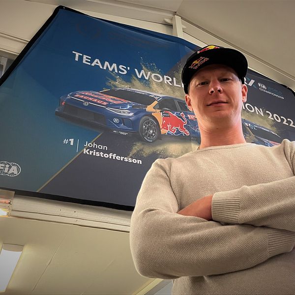 Rallycrossföraren och regerande världsmästaren Johan Kristoffersson står framför en plansch med sin tävlingsbil.