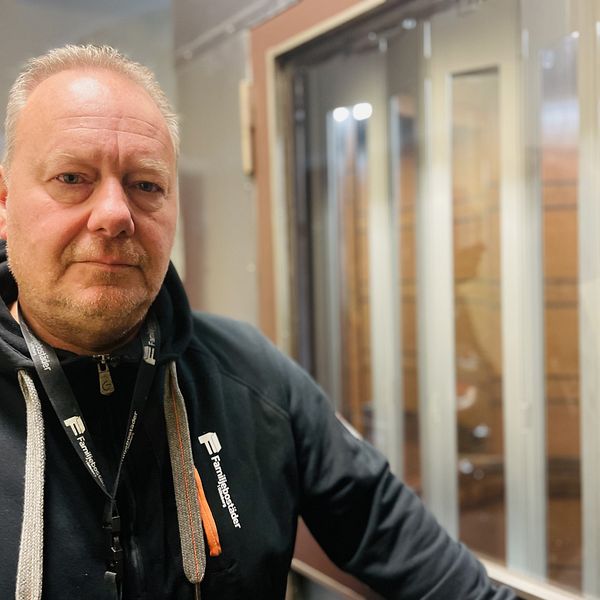 En man med svart tröja står framför en hiss.