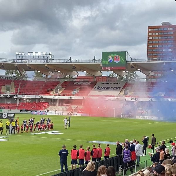 Röd och blå rök från pyroteknik på läktaren.