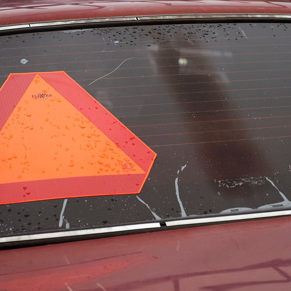 Baksidan av en bil med en röd-orange varningstriangel på bakrutan.