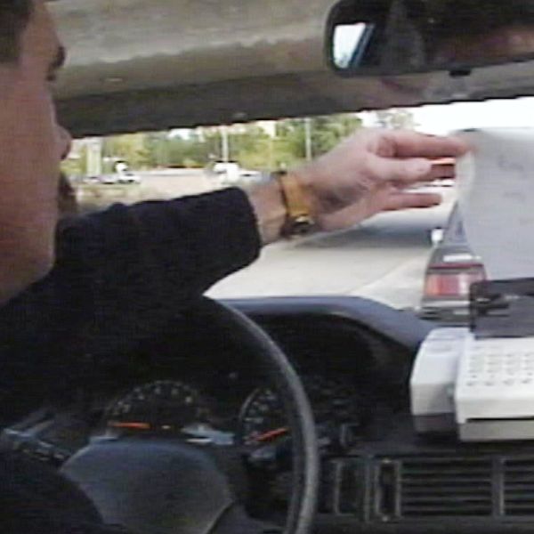 En man som tar ett papper från faxmaskin i en bil.