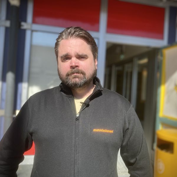 En man i svart tröja och skägg ser allvarlig ut