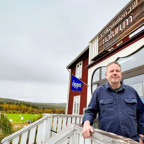 Ola Fransson står på trappan utanför Naturum i Vålådalen med ett landskap i höstskrud i bakgrunden.