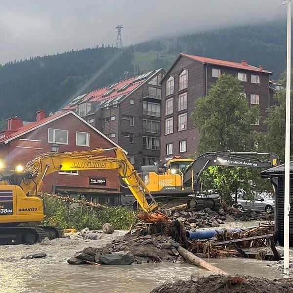 Åre by. Översvämning vatten och en grävmaskin i förgrunden. Åreskutan i bakgrunden.