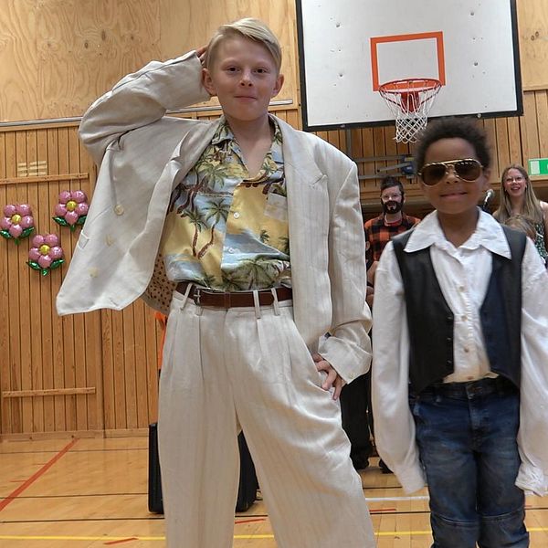 Elever i Lillhärdal bjuder på modeshow – klädda i 80-talskläder, Pojke i vit kostym och pojke i mörke solglasögon frontar