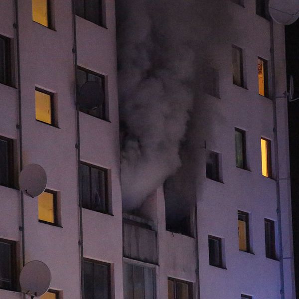 Det brinner på fjärde våningen i ett lägenhetshus i Bredäng, Stockholm på söndagsmorgonen. Rök stiger upp ur fönster.