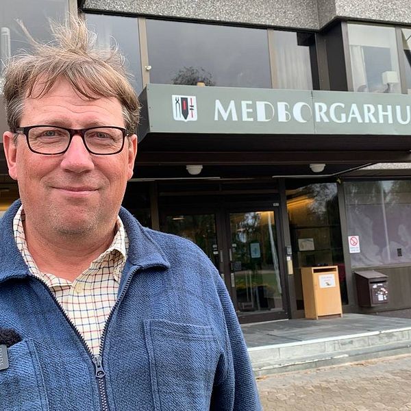 Man med brunt hår och glasögon står framför medborgarhuset i Sveg. Mannen har blå skjorta på sig.